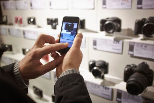 Mid Adult Man Photographing Cameras In Shop Display Using Smartphone Picture Id492688443