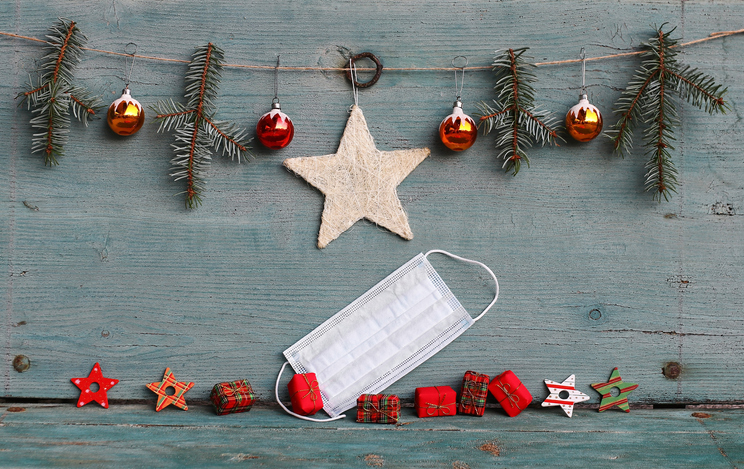  protective mask next to Christmas tree balls, fir branches and gift packages