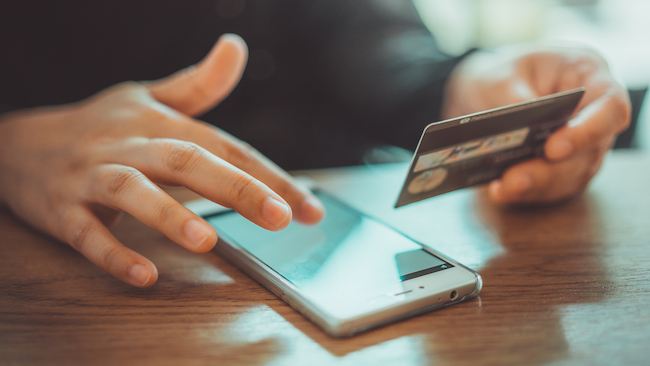 Photo of someone typing credit information into phone.