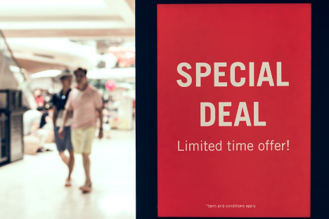 red sign with off-white text next to shoppers that says special deal limited time offer! 